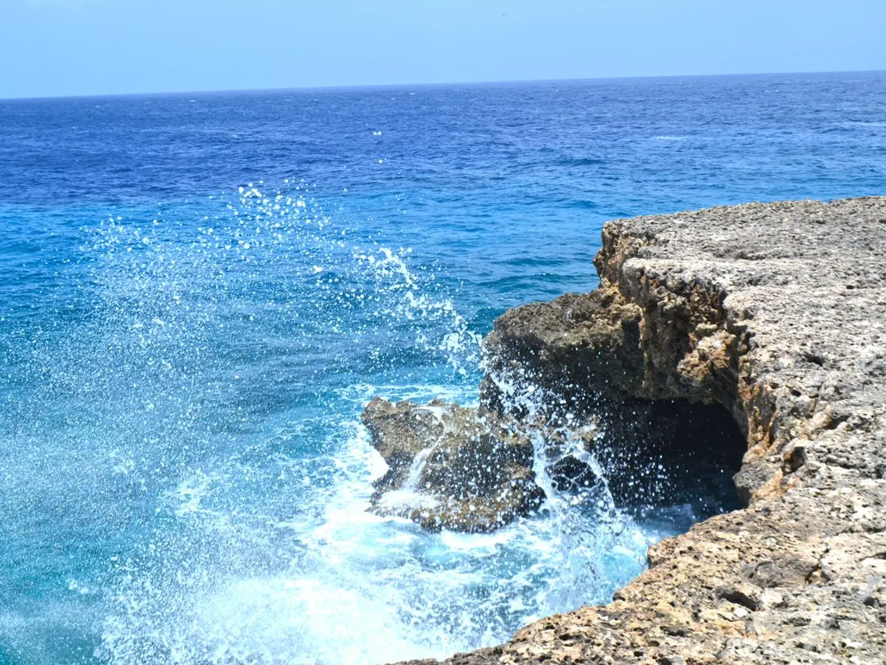 Opspattend zeewater tegen de rotskust bij de Blue Room Cave aan de westkust van Curaçao